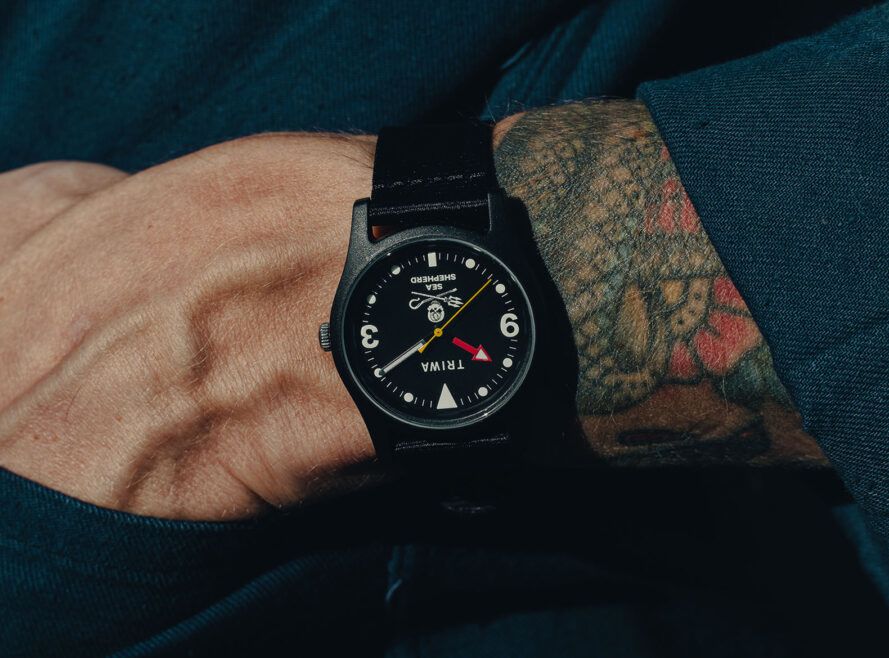 A tattooed arm with a watch on the wrist.