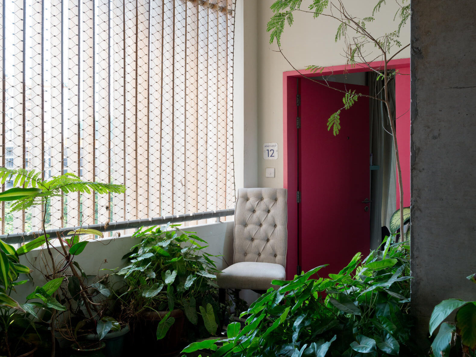 Red apartment entry door surrounded by plants
