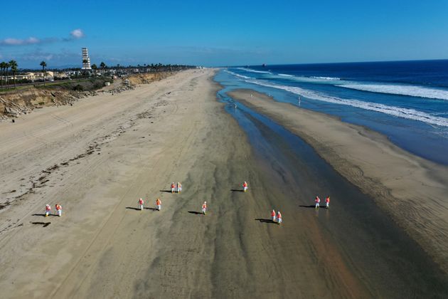 Environmental cleanup crews pick oil chucks off Huntington Dog Beach in Huntington Beach,