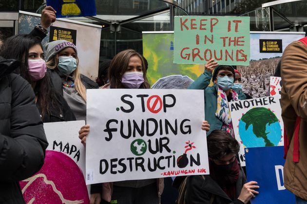 Youth climate activists protest financing fossil fuel projects outside Standard Chartered headquarters...