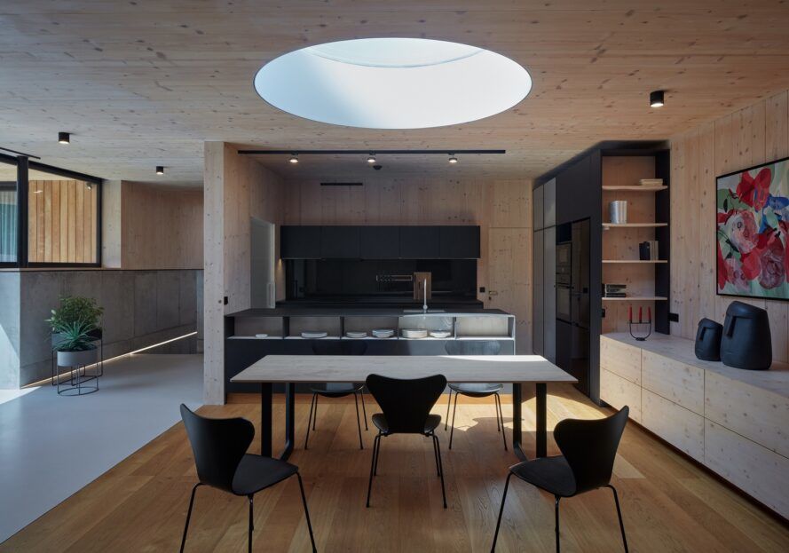 A kitchen area with a table and three chairs with a cut out circle on the ceiling
