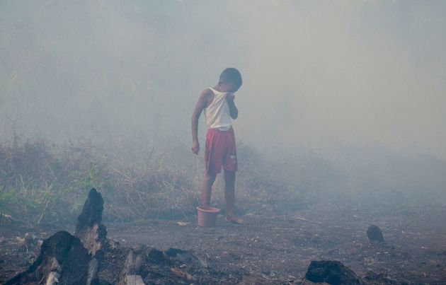 A young boy covers his eyes as smoke shrouds his neighborhood in